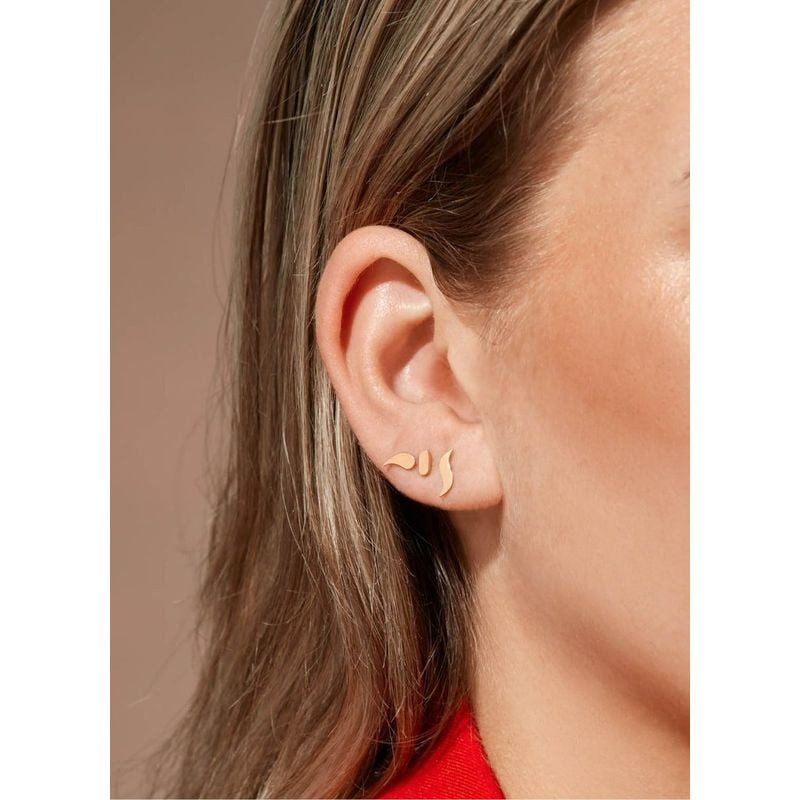 Gros plan sur une oreille portant des clous d'oreilles Jackie Gold Carnaval en or 14 carats dans un 