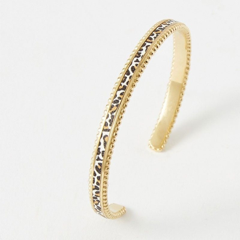 Bracelet jonc ouvert doré avec cuir blanc imprimé léopard et bords perlés, vue produit inclinée