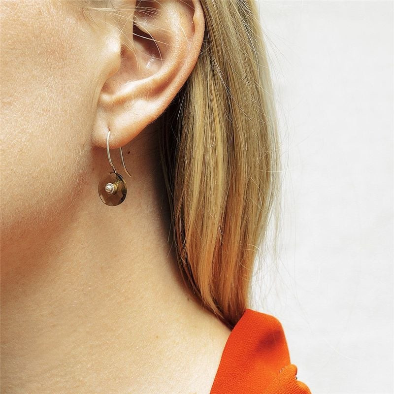 Modèle portant un pendentif d'oreille Trollbeads en quartz fumé sur un crochet argenté, gros plan or