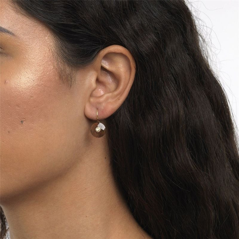 Gros plan d'un pendentif Trollbeads en quartz fumé facetté porté à l'oreille d'un mannequin aux chev