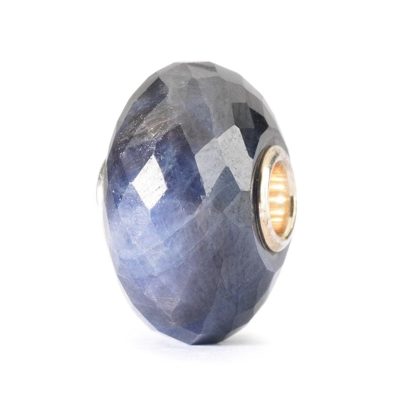 Vue de côté de la perle Trollbeads Saphir révélant son cœur doré et sa surface en saphir bleu facett