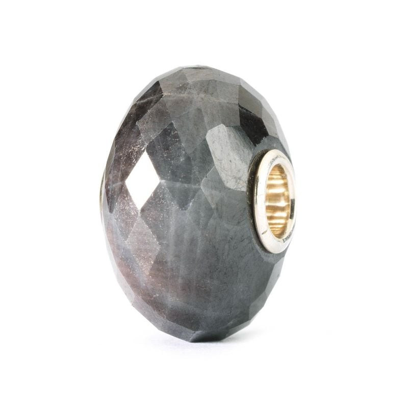Vue inclinée et sombre de la perle Trollbeads Saphir facettée, révélant son bleu profond et son cœur