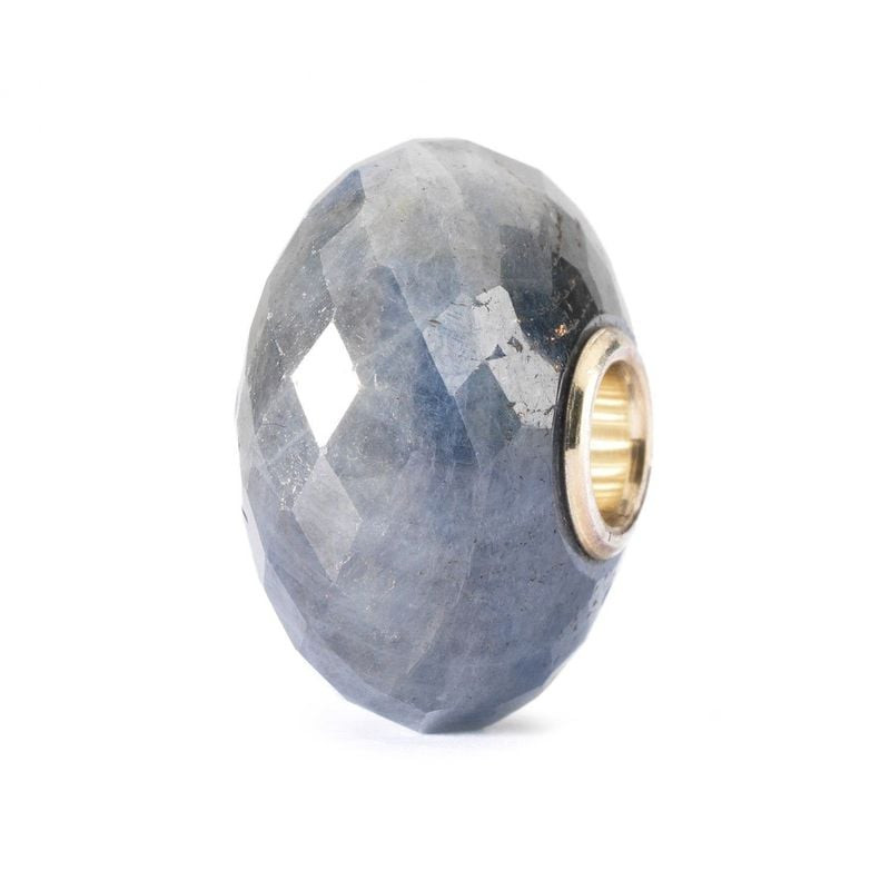 Vue inclinée de la perle Trollbeads Saphir dévoilant ses facettes captant la lumière et son cœur mét