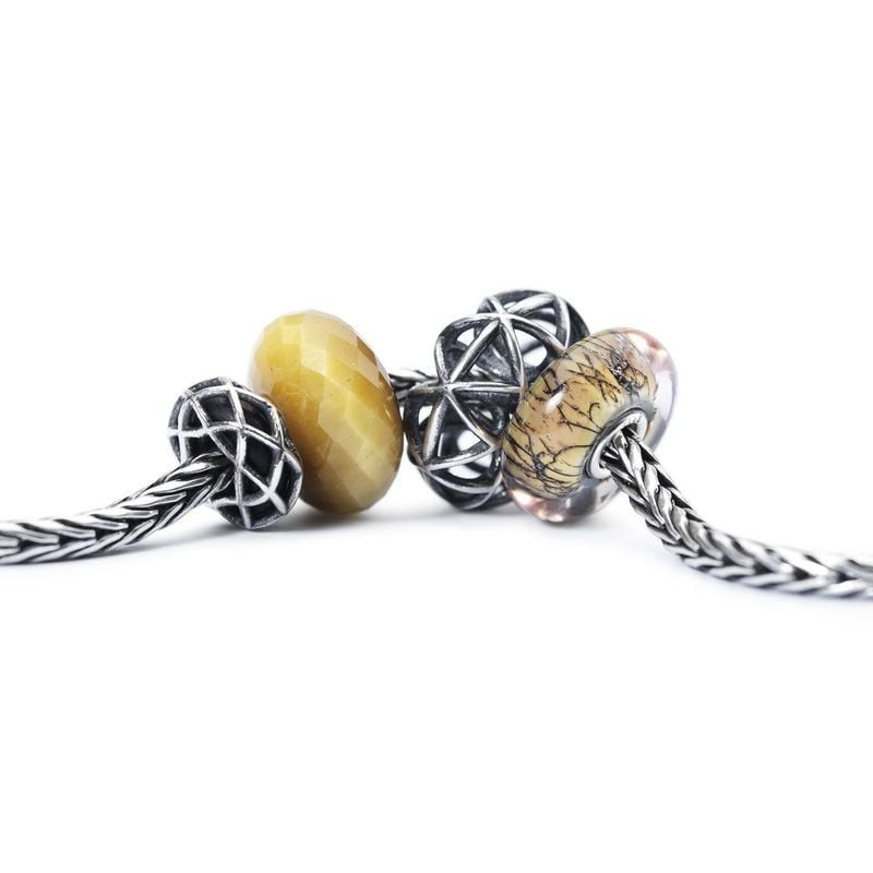 Gros plan du charme Trollbeads quartz œil-de-chat sur chaîne argent avec motif étoilé et perles de v