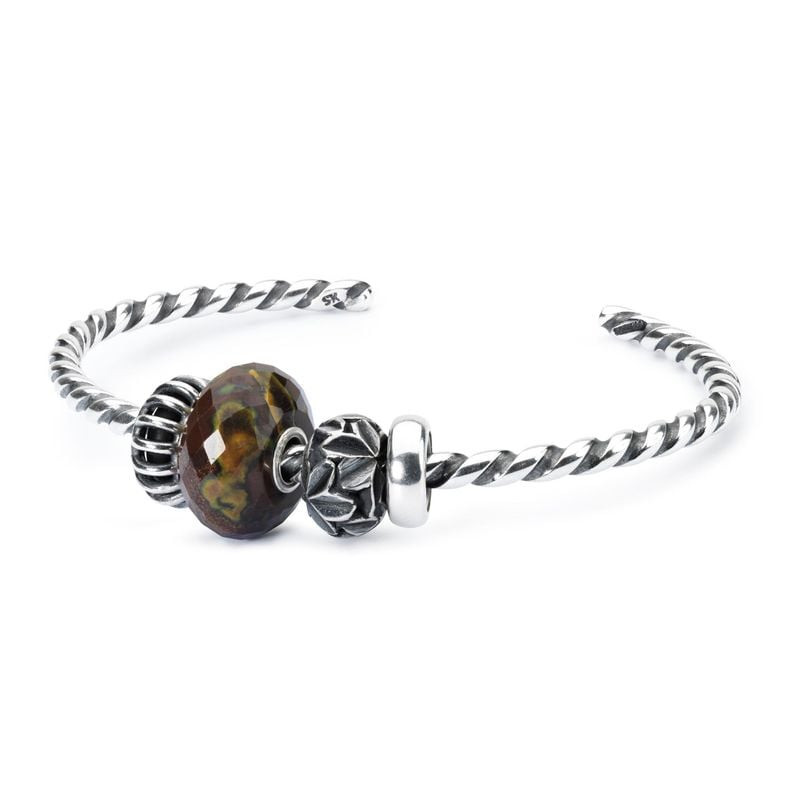 Bille de calcite Trollbeads facettée enfilée sur un jonc torsadé en argent avec un charm en argent à