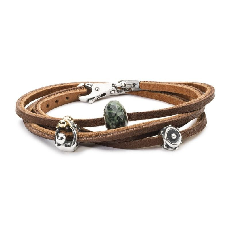 Bracelet Trollbeads en cuir marron avec perle en pierre verte facettée et charms en argent sur fond 