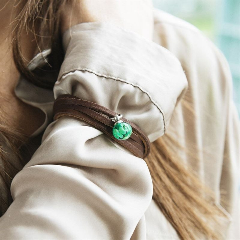 Mannequin portant un bracelet Trollbeads en cuir marron avec une perle en verre verte sur une manche