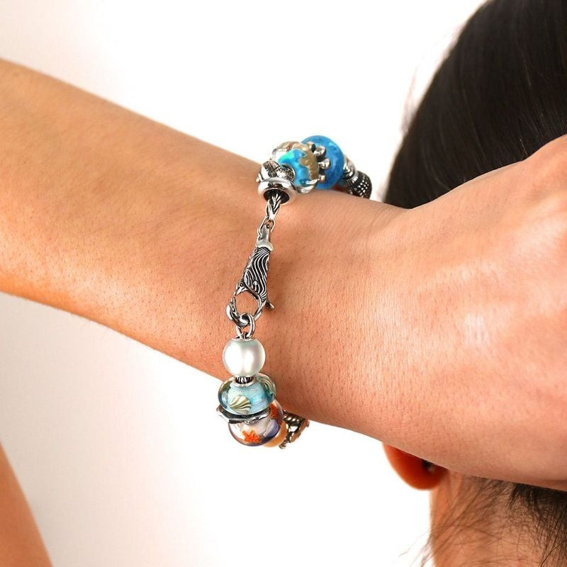 Perle de verre Trollbeads Cadeau de la Marée portée sur un bracelet au poignet avec des charms