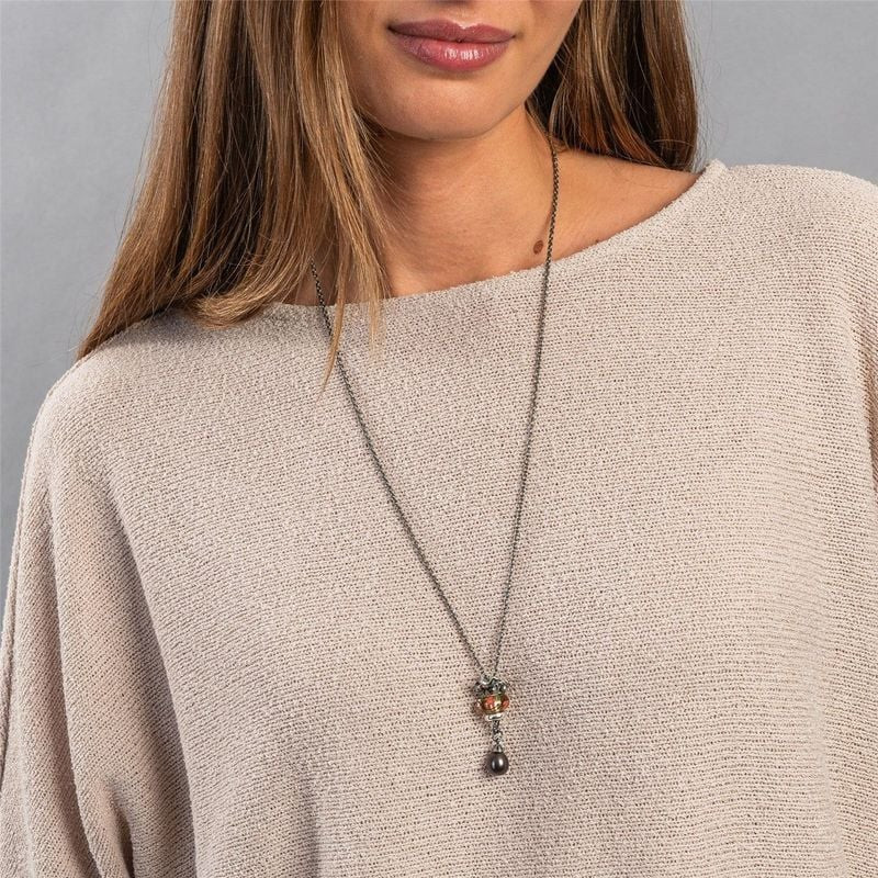 Gros plan de la perle Trollbeads Love in Bloom sur collier en argent avec breloque perle, portée sur