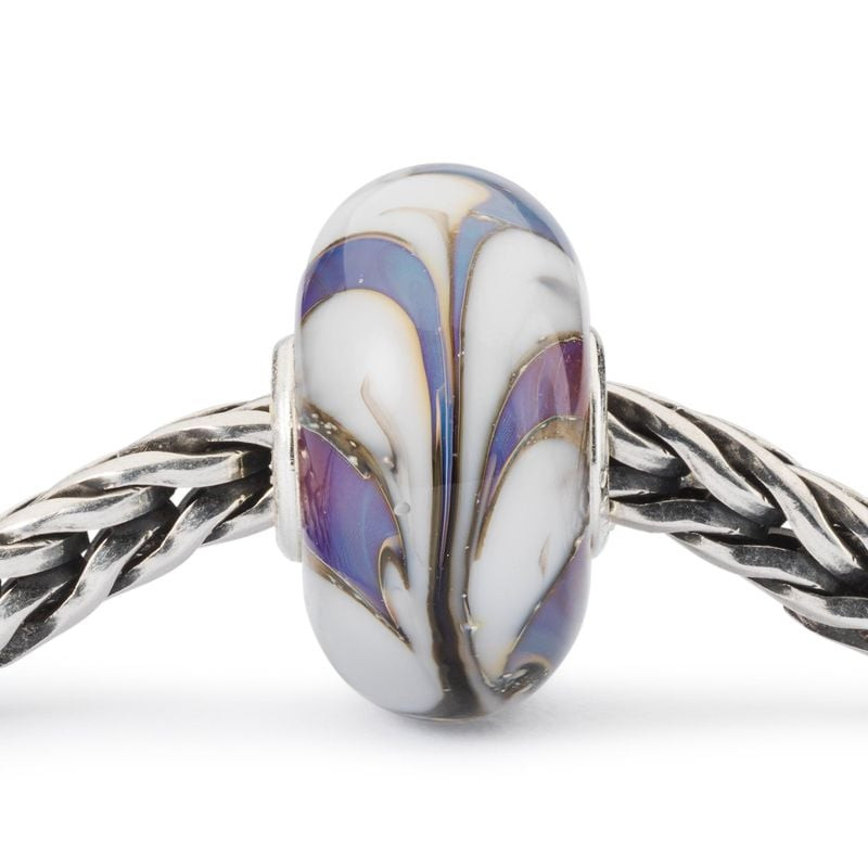 Gros plan sur la perle en verre Colombe de Trollbeads sur une chaîne en argent tressé, détails dorés