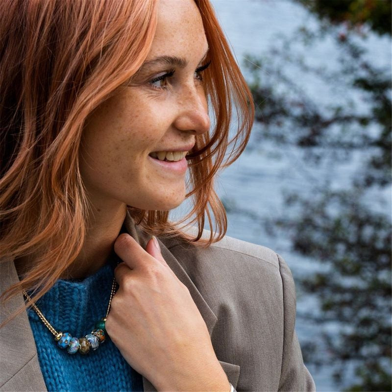 Femme aux cheveux roux portant un collier Trollbeads aux perles de verre multicolores