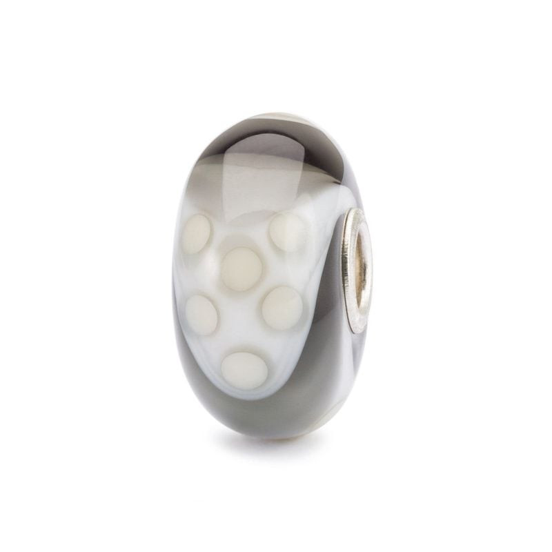Perle en verre TROLLBEADS SOPHISTICATED ARMADILLO avec points blancs sur fond gris.