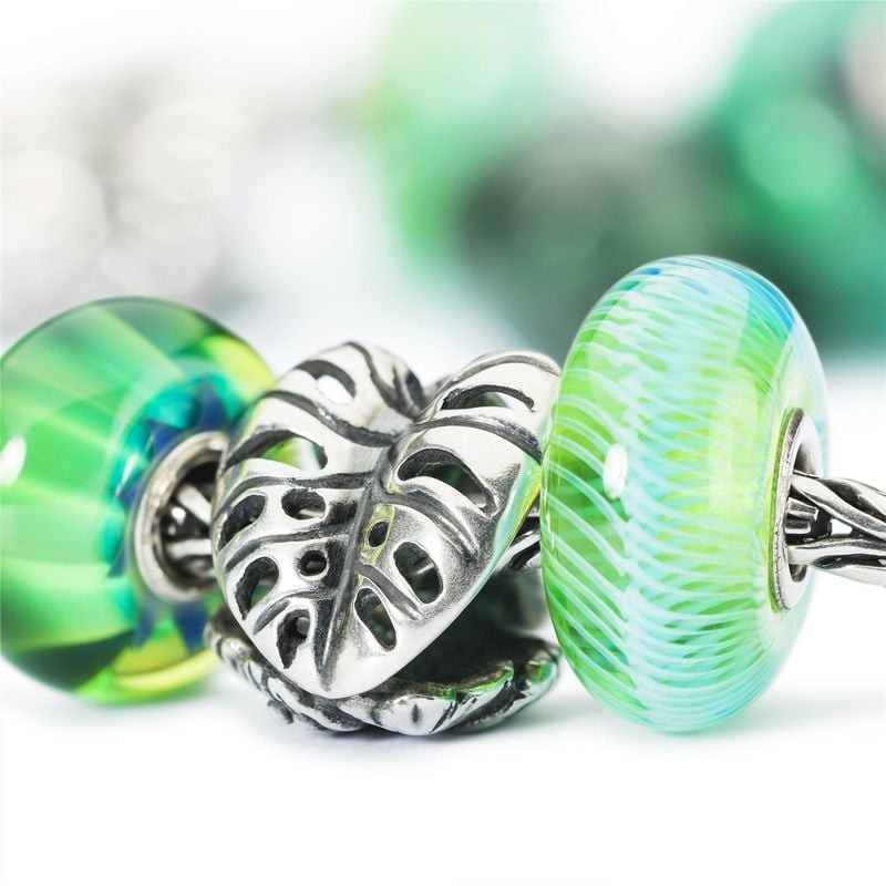 Perle Trollbeads Plume turquoise avec perles en verre vert et breloque feuille en argent sur fond bl