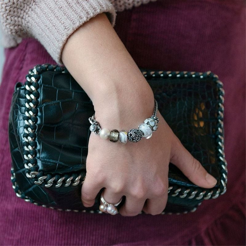 Bracelet Trollbeads porté au poignet d'une femme avec la perle en verre Acier blanc parmi des perles