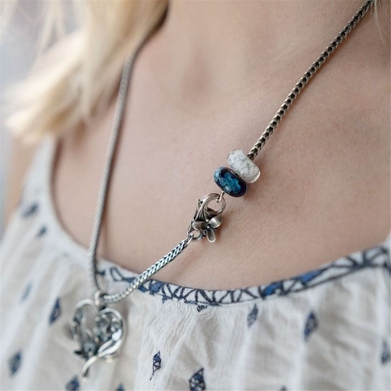 Perle Trollbeads Acier blanc portée sur une chaîne de collier en argent avec une perle en verre bleu