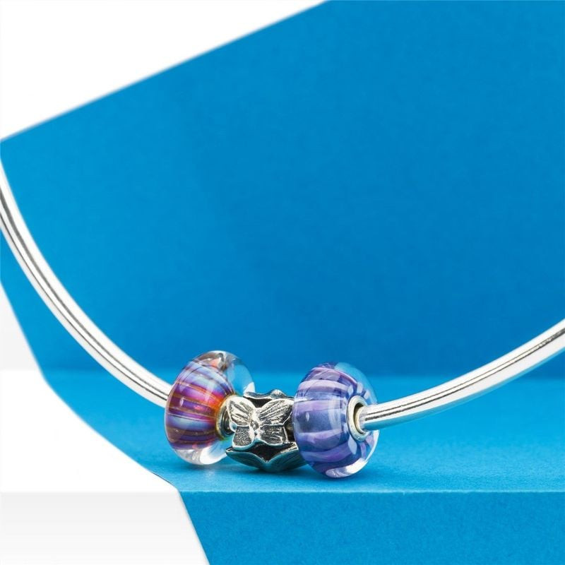 Perle en verre Trollbeads Rayure d'aurore portée sur un bracelet argenté avec d'autres perles sur fo