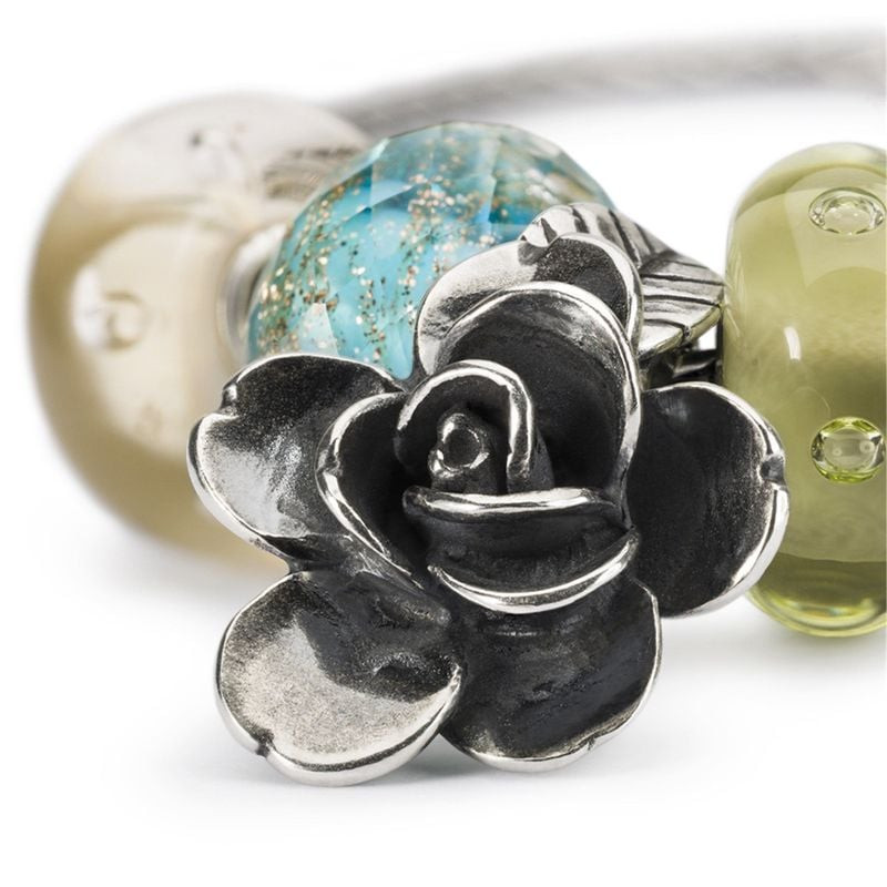 Gros plan du pendentif Trollbeads Rose de la Beauté en argent, pétales superposés et feuille gravée 