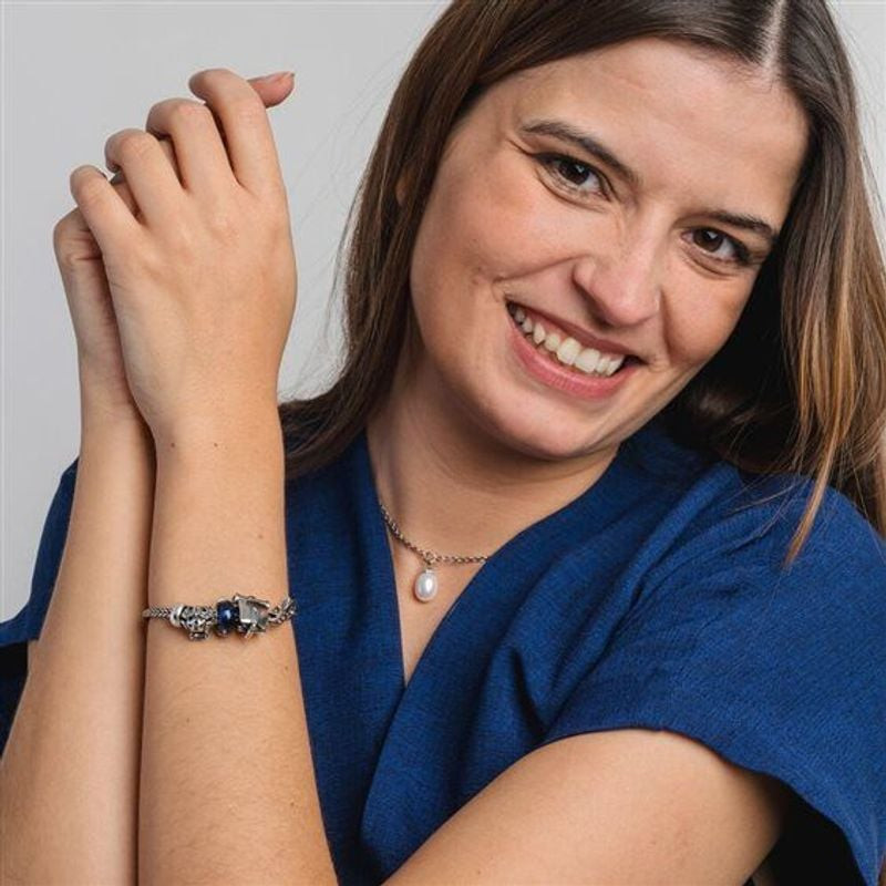 Femme souriante portant un bracelet Trollbeads avec le Fermoir Gouttes de sagesse et un collier de p