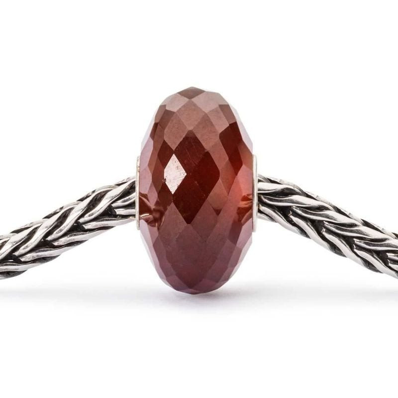 Charm Trollbeads Facetté Grenat Hessonite Rouge sur fond d'ambiance élégante et chaleureuse