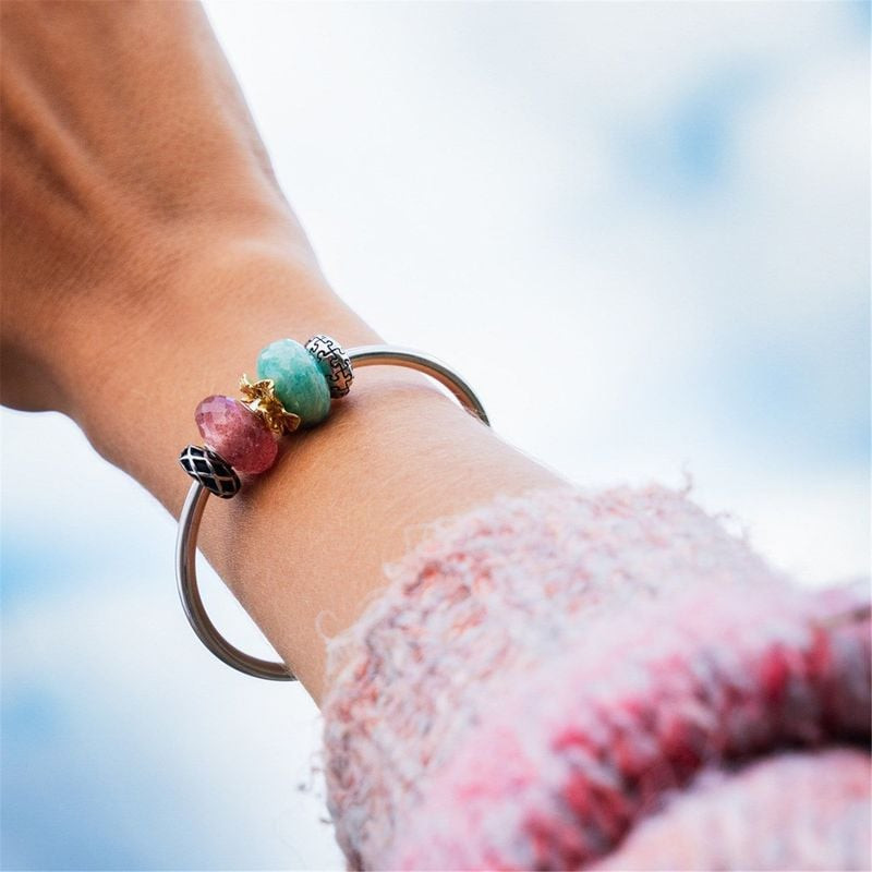 Femme portant le Charm Trollbeads Fraise Pierre Rose sur un bracelet en argent, dans un cadre élégan