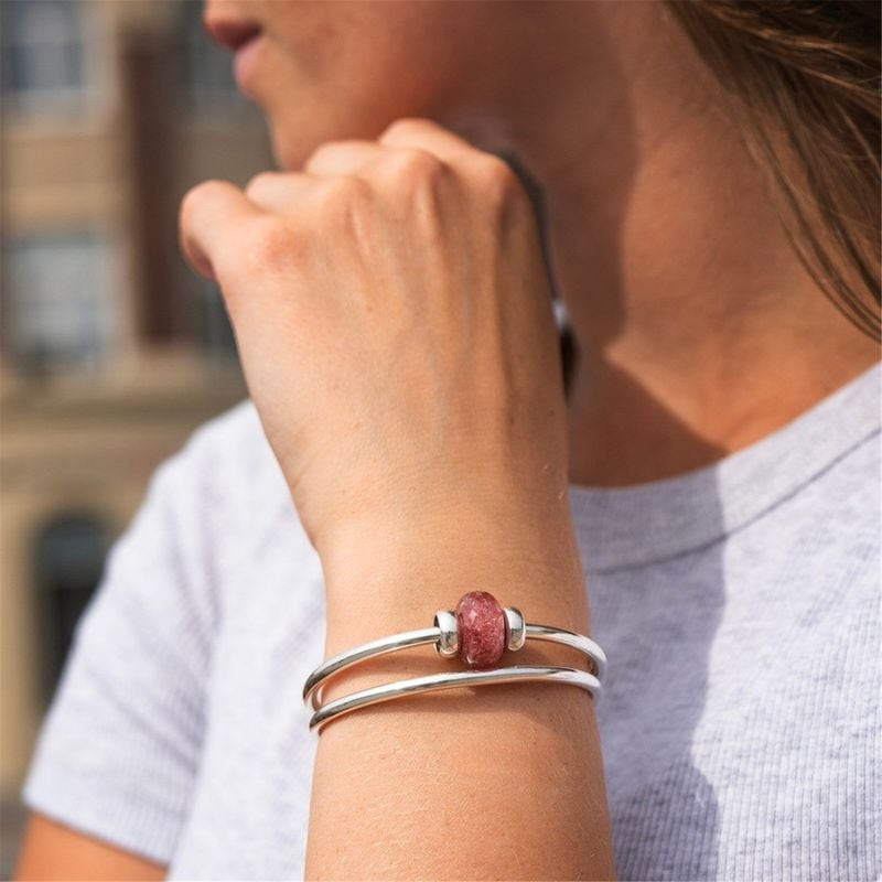 Charm Trollbeads Fraise Pierre Rose porté sur un bracelet, ambiance lifestyle élégante