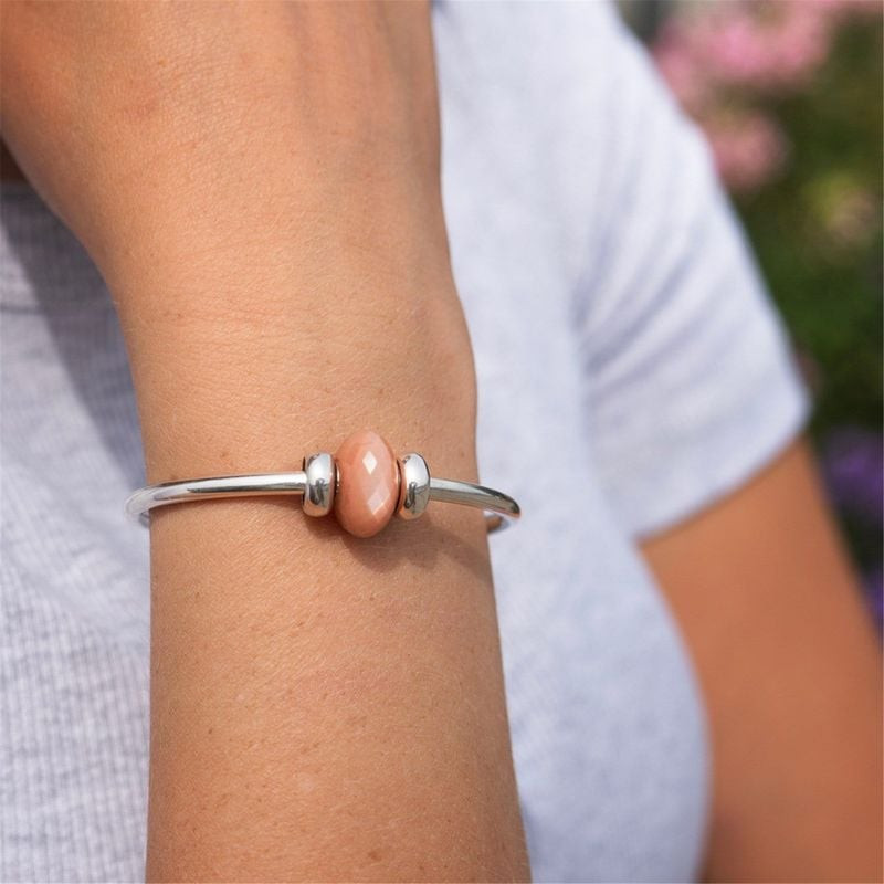 Poignet portant la Perle Charm Trollbeads Feldspar Moonstone Pierre de Lune, reflets saumon naturels
