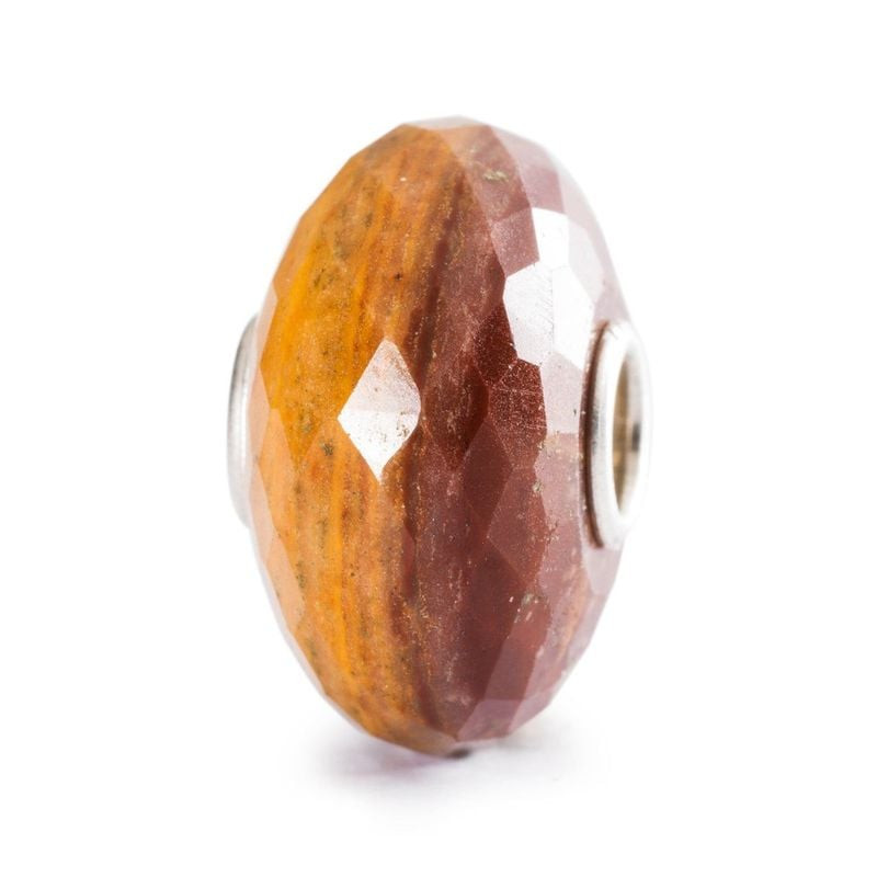 Vue inclinée de la perle Trollbeads en calcédoine marron et jaune, bandes facettées orange chaud et 