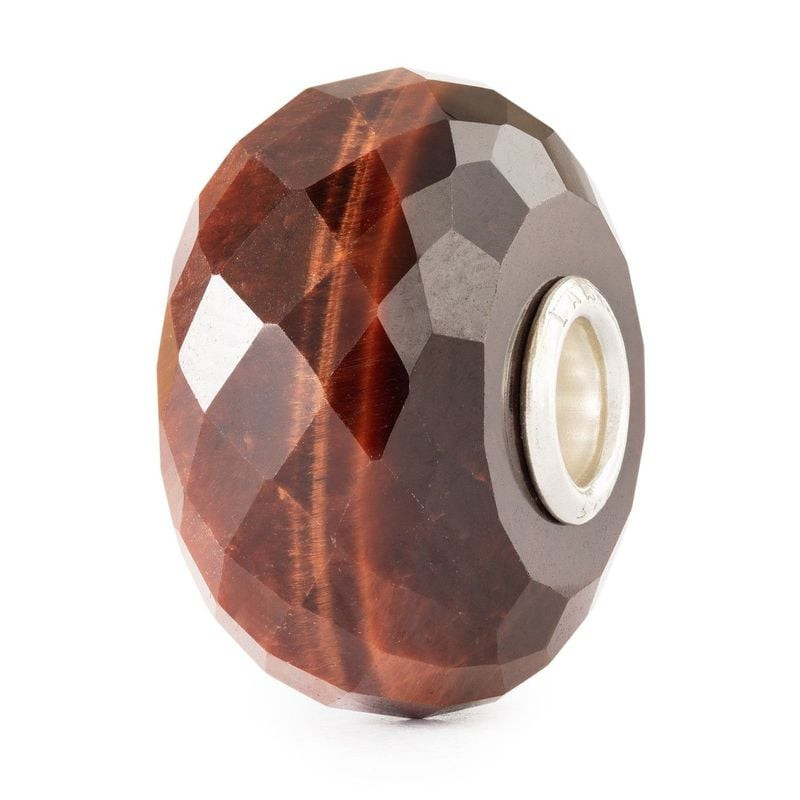 Perle Trollbeads facettée en œil de tigre rouge avec âme en argent 925, vue de trois quarts sur fond