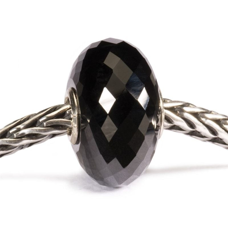 Gros plan de la perle Trollbeads en onyx noir facetté enfilée sur une chaîne en argent tressé