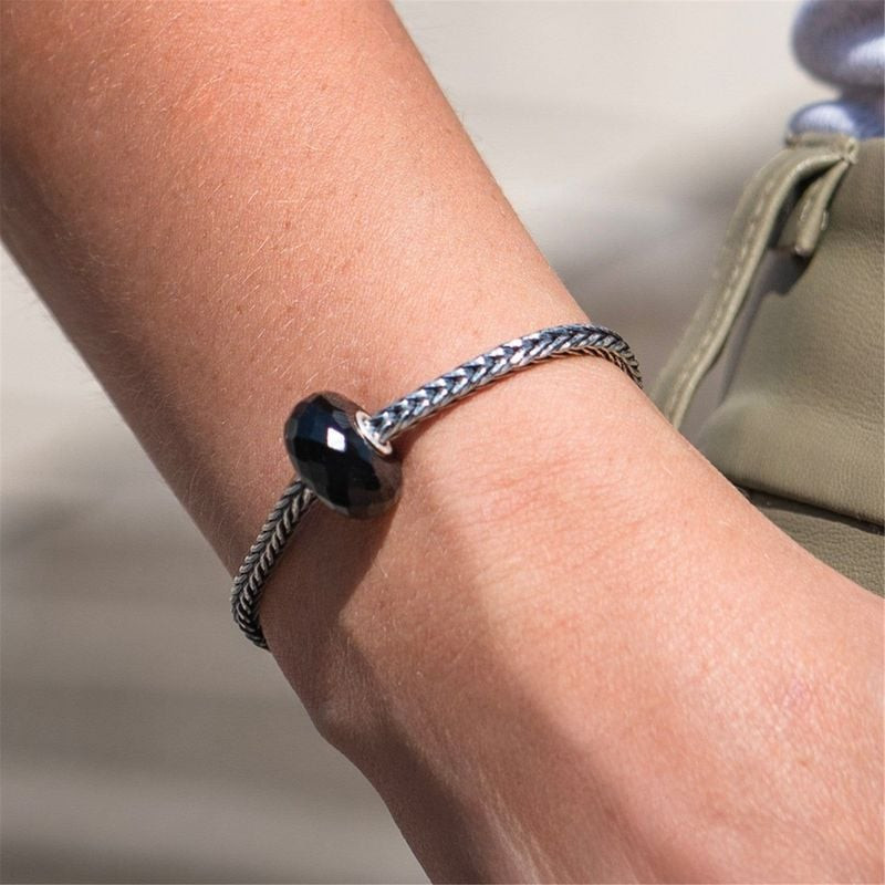 Femme portant une perle Trollbeads Onyx noir sur un bracelet en argent tressé en lumière naturelle