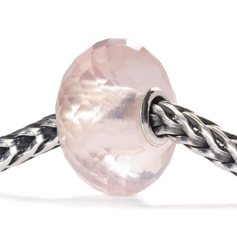 Gros plan d'une perle Trollbeads en quartz rose à facettes sur une chaîne en argent.