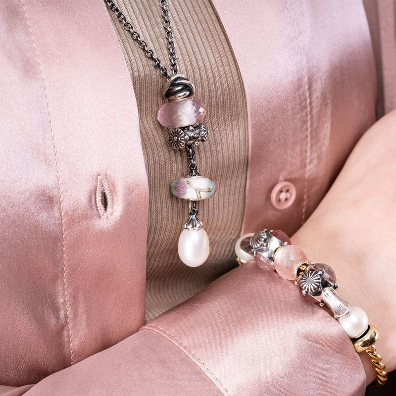 Gros plan d'une femme portant des bijoux Trollbeads, dont une perle en quartz rose sur un bracelet e