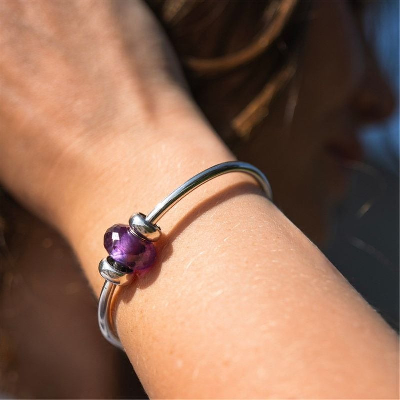 Perle Trollbeads améthyste sur bracelet argenté lisse entre deux stoppeurs argentés au soleil