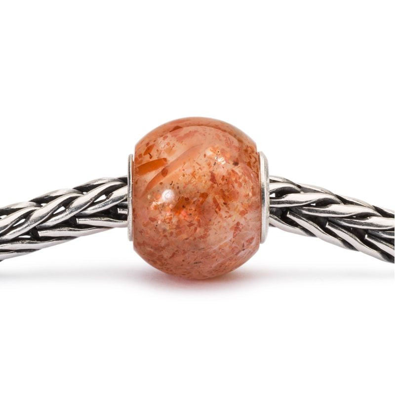 Perle Trollbeads Ronde en Pierre de Soleil dans une ambiance dorée et chaleureuse