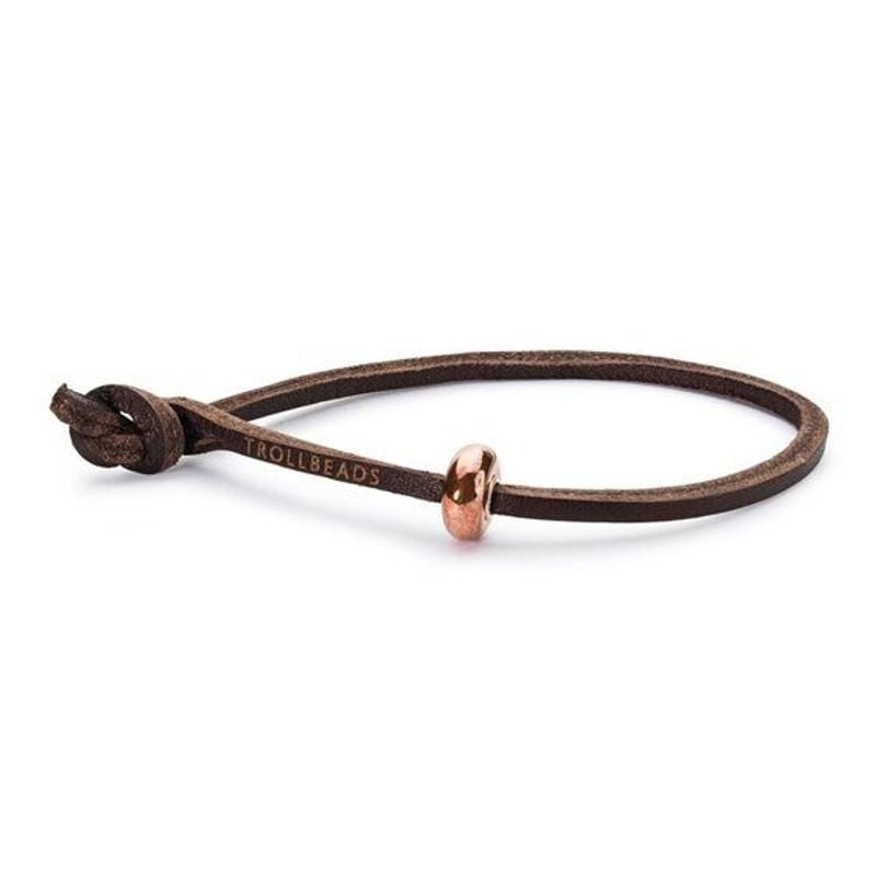 Bracelet Trollbeads en cuir marron sur fond blanc avec un charm or rose enfilé sur le cordon ajustab