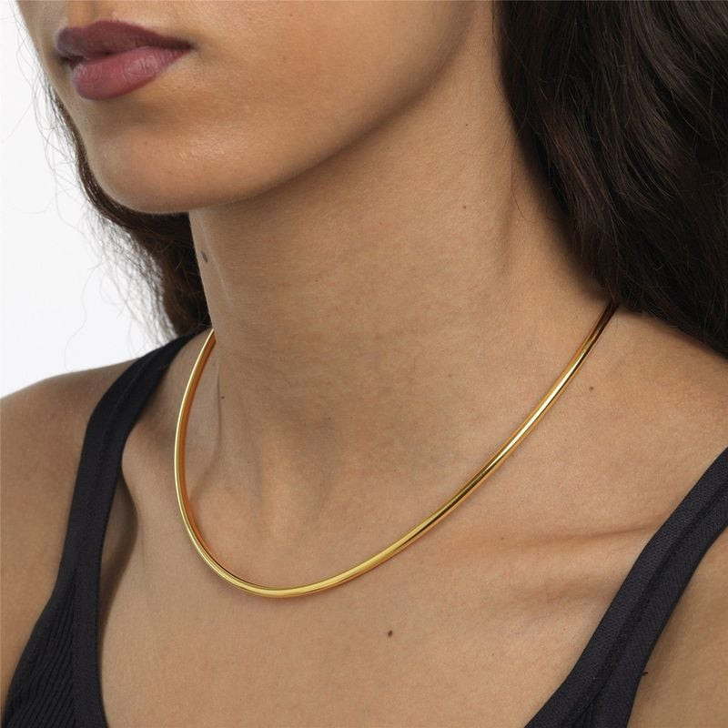 Femme portant le collier torque Trollbeads plaqué or taille S au cou avec un débardeur noir