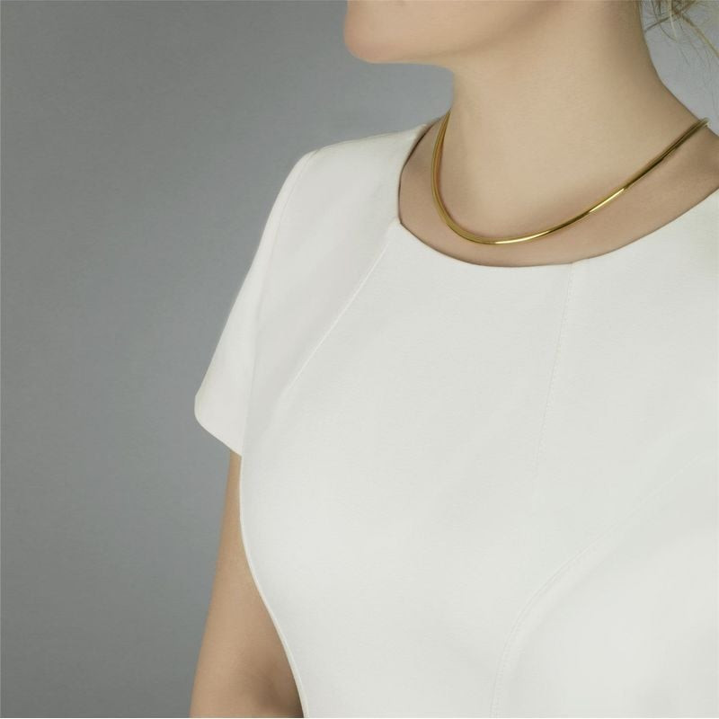 Collier torque Trollbeads en vermeil doré taille S porté sur un haut blanc sur fond gris