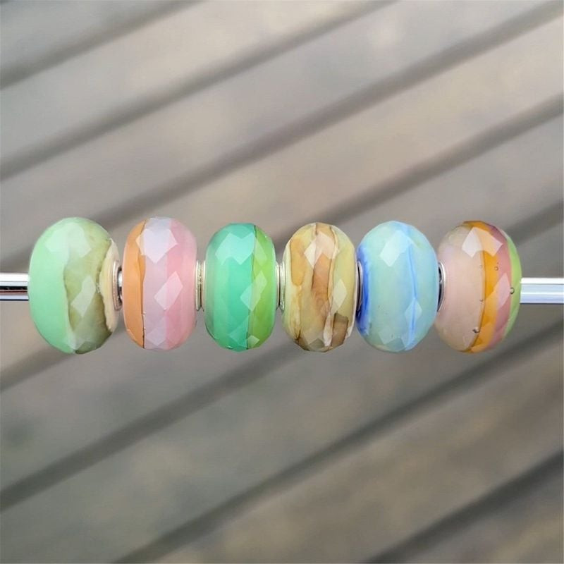 Sélection de perles Trollbeads sur une tige métallique, dont la perle TROLLBEADS PIERRE D EAU SAUGE 