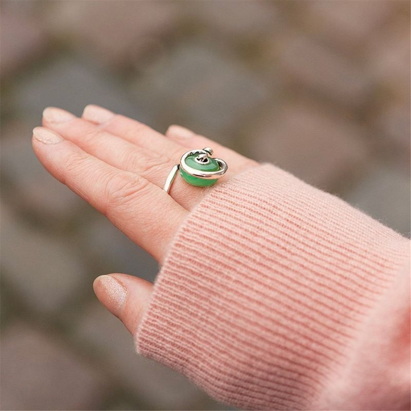 Gros plan d'une main portant une bague ornée de la perle TROLLBEADS PIERRE D'EAU SAUGE.