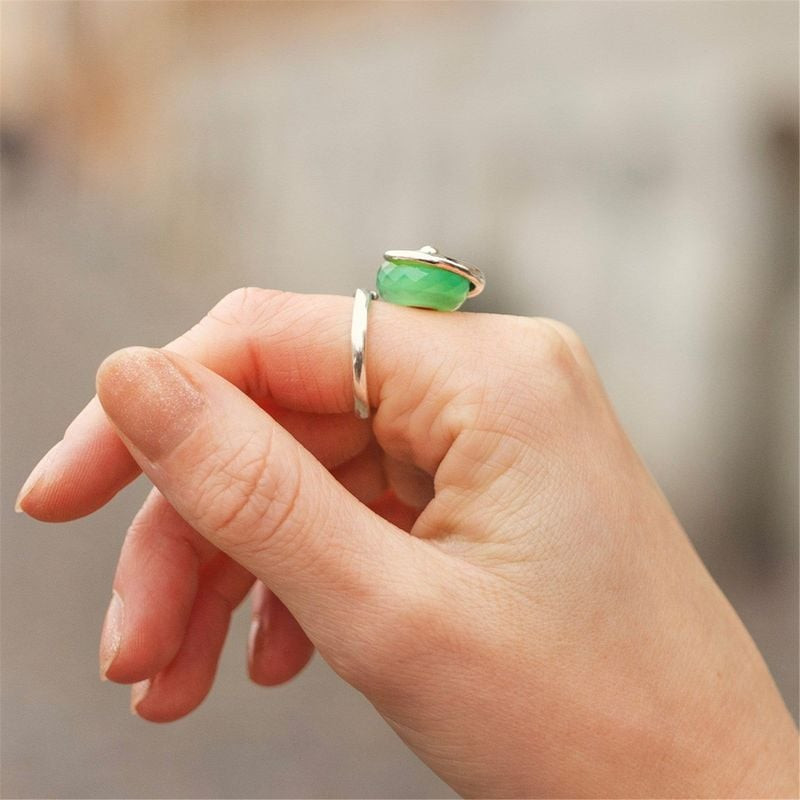 Doigts ornés de bagues, dont une avec la perle TROLLBEADS PIERRE D'EAU SAUGE.