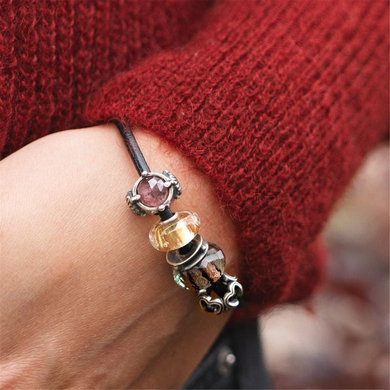 Perle Trollbeads Plaisirs d'Hiver portée au poignet avec pierres roses et perles ambre sur maille ro