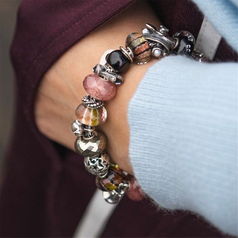Gros plan sur la perle Trollbeads Plaisirs d'Hiver sur un bracelet à charms superposés avec des perl