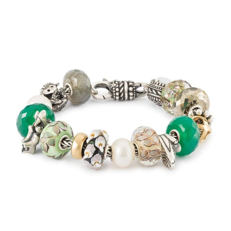 Assortiment de Trollbeads sur un bracelet, avec la perle FEUILLES OSCILLANTES, des pierres vertes et