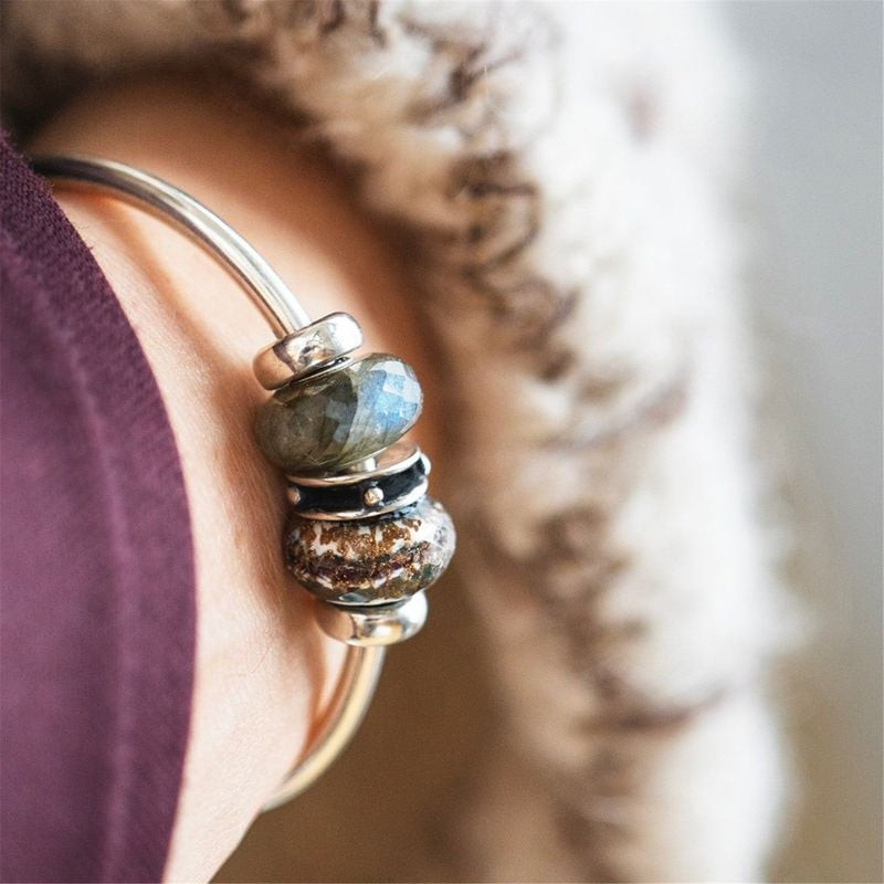Perle Trollbeads Trésors en Or en verre noir et blanc portée sur un bracelet Trollbeads