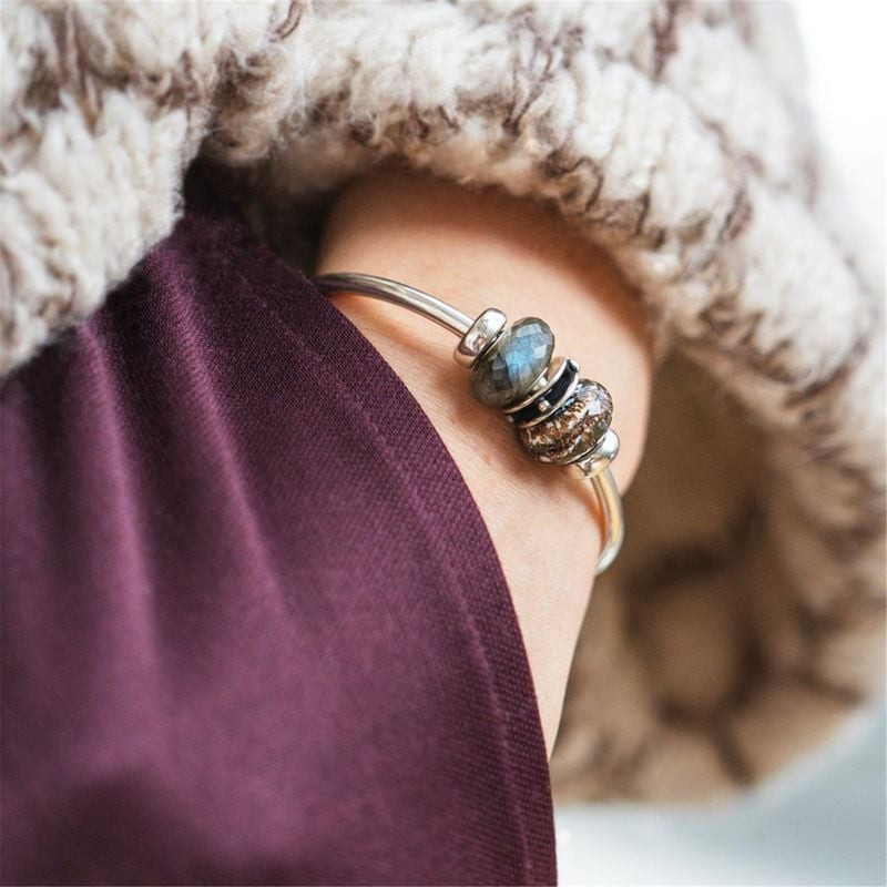Perle Trollbeads Trésors en Or en verre noir et blanc portée sur un bracelet, reflets dorés