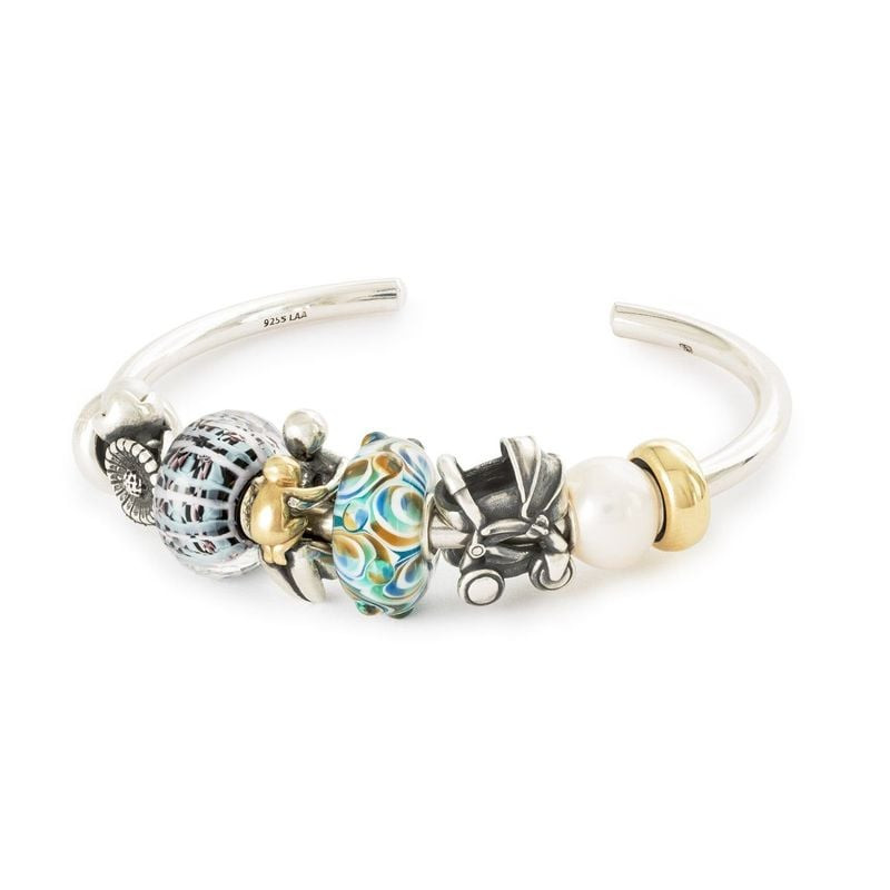 La perle Panier de la Sérénité présentée sur un jonc Trollbeads en argent avec des breloques en or, 