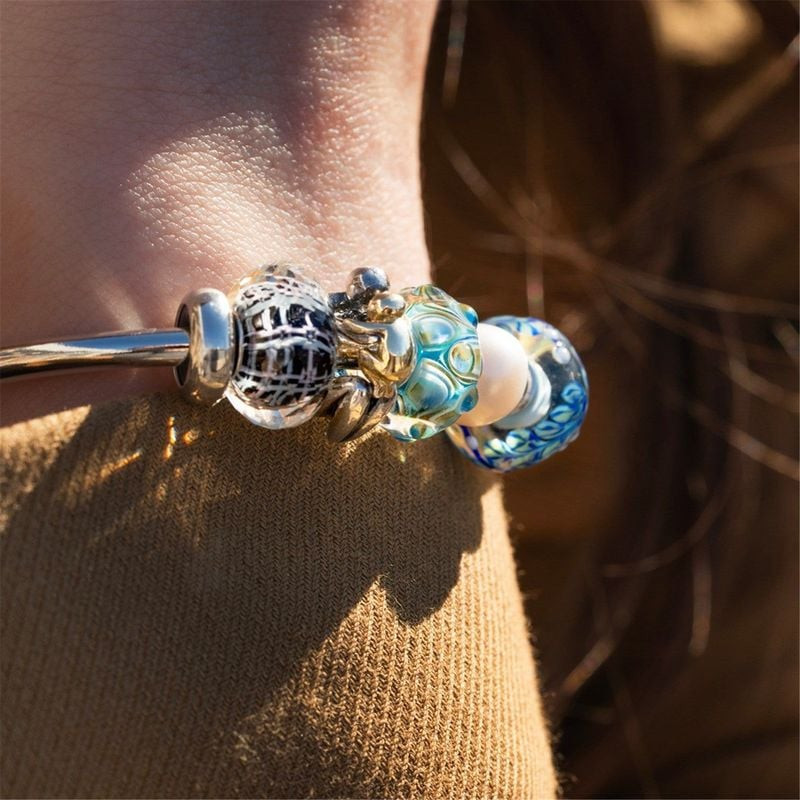 Perle en verre Panier de la Sérénité sur un jonc en argent, portée sous une lumière chaude dans un d