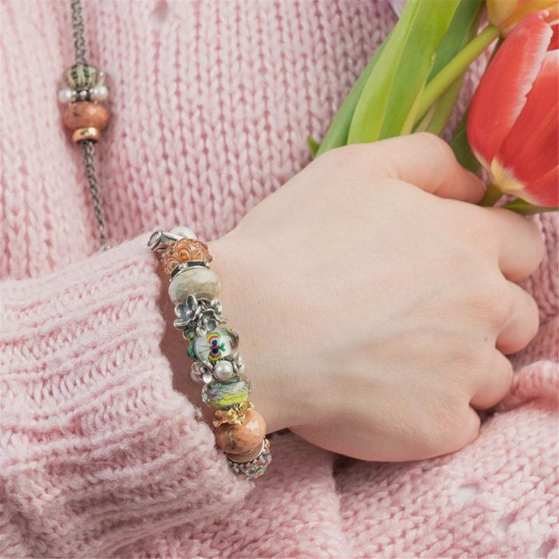 Bracelet de perles en verre Trollbeads avec la perle Vie Actuelle porté au poignet, pull en maille r