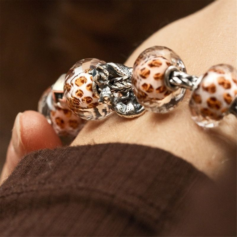 Plusieurs perles en verre Trollbeads Taches de Léopard et un charm léopard en argent portés au poign