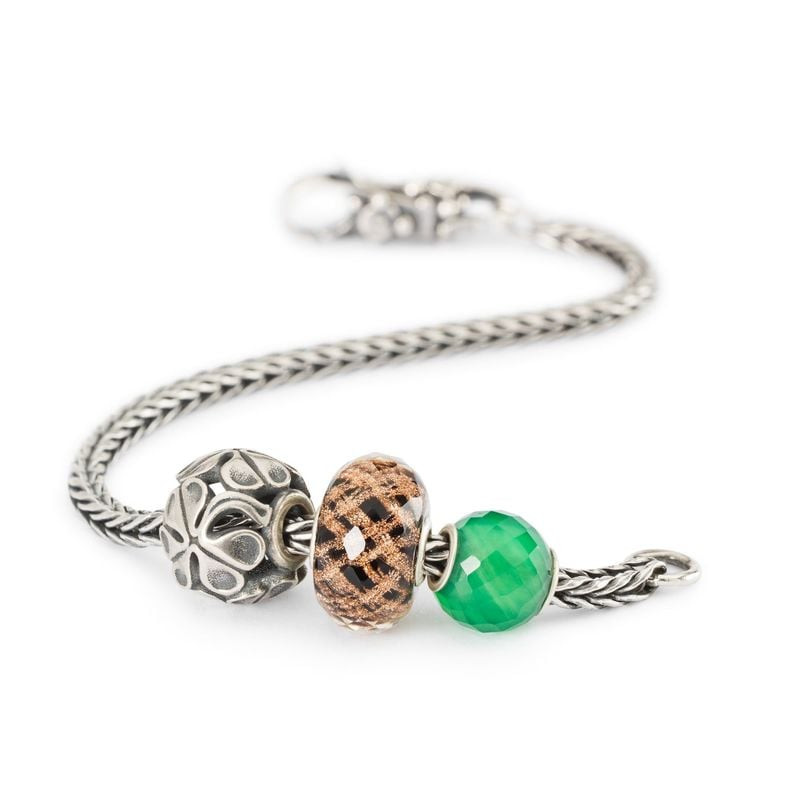 Perle Trollbeads Happy 2023 portée sur une chaîne de bracelet en argent avec des charms verts et arg